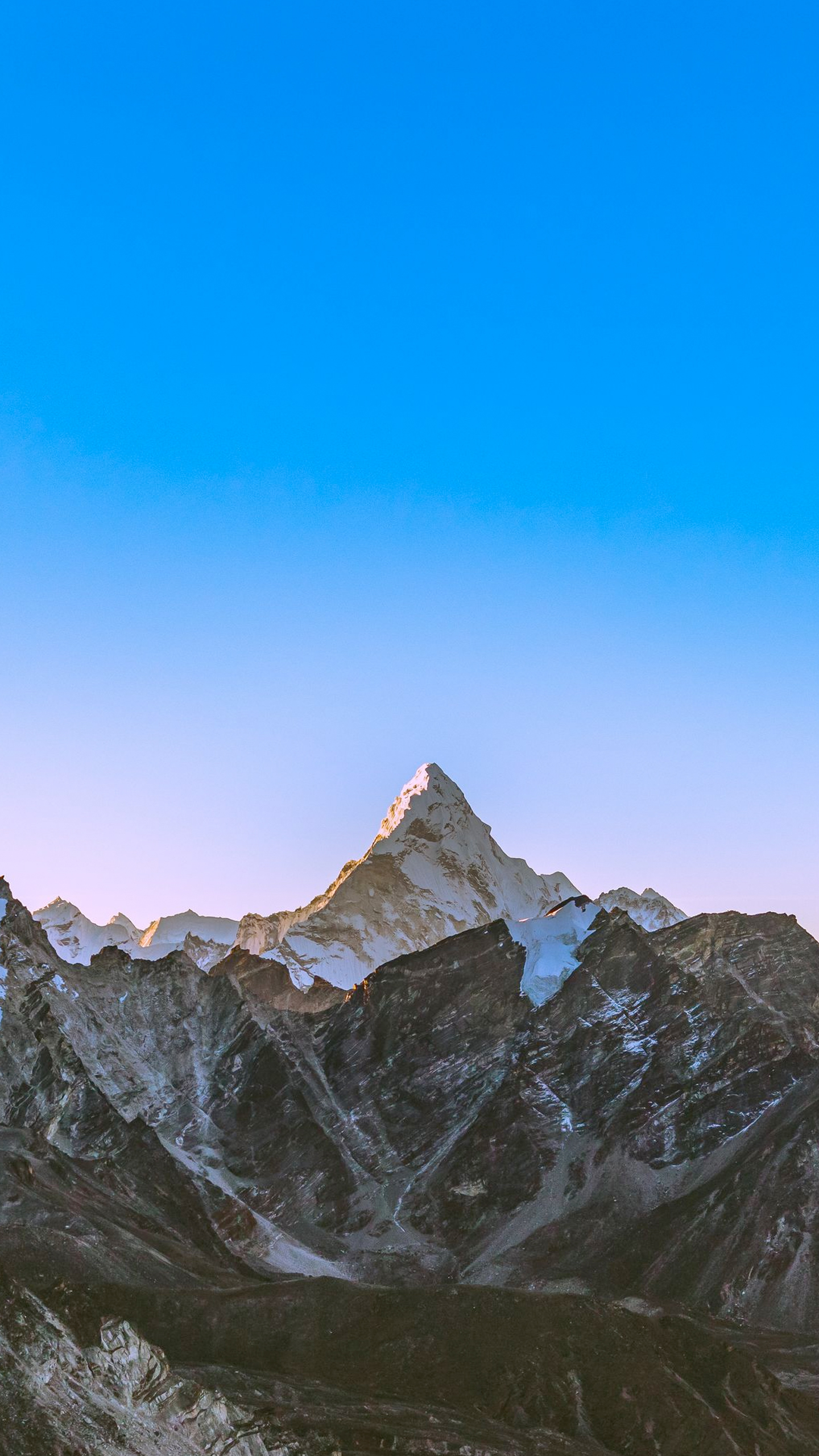 Snow-capped mountain peaks stretch towards a vibrant blue sky.
