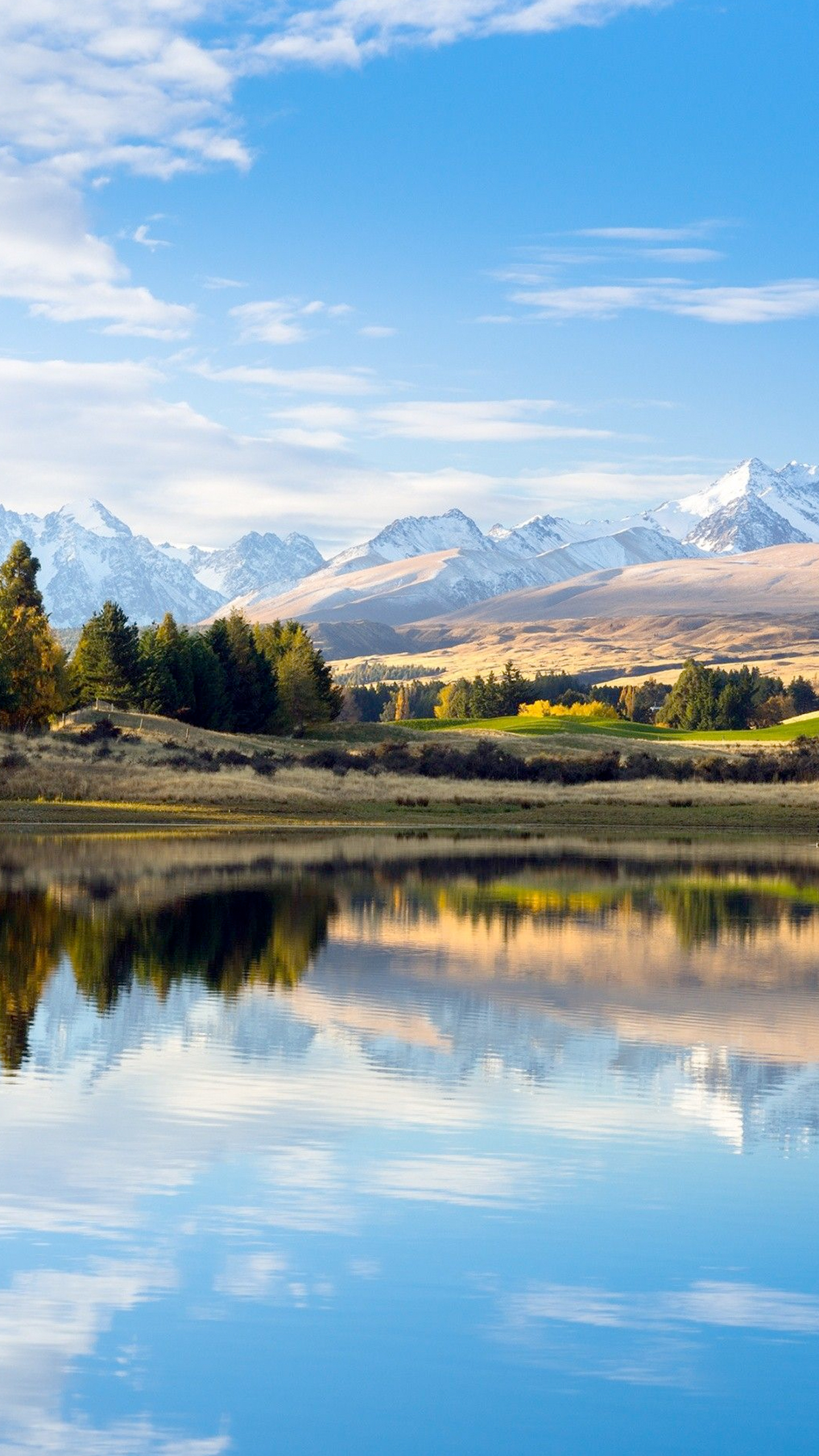 A serene landscape unfolds, with snow-capped mountains rising in the distance, their peaks glistening in the sunlight.
