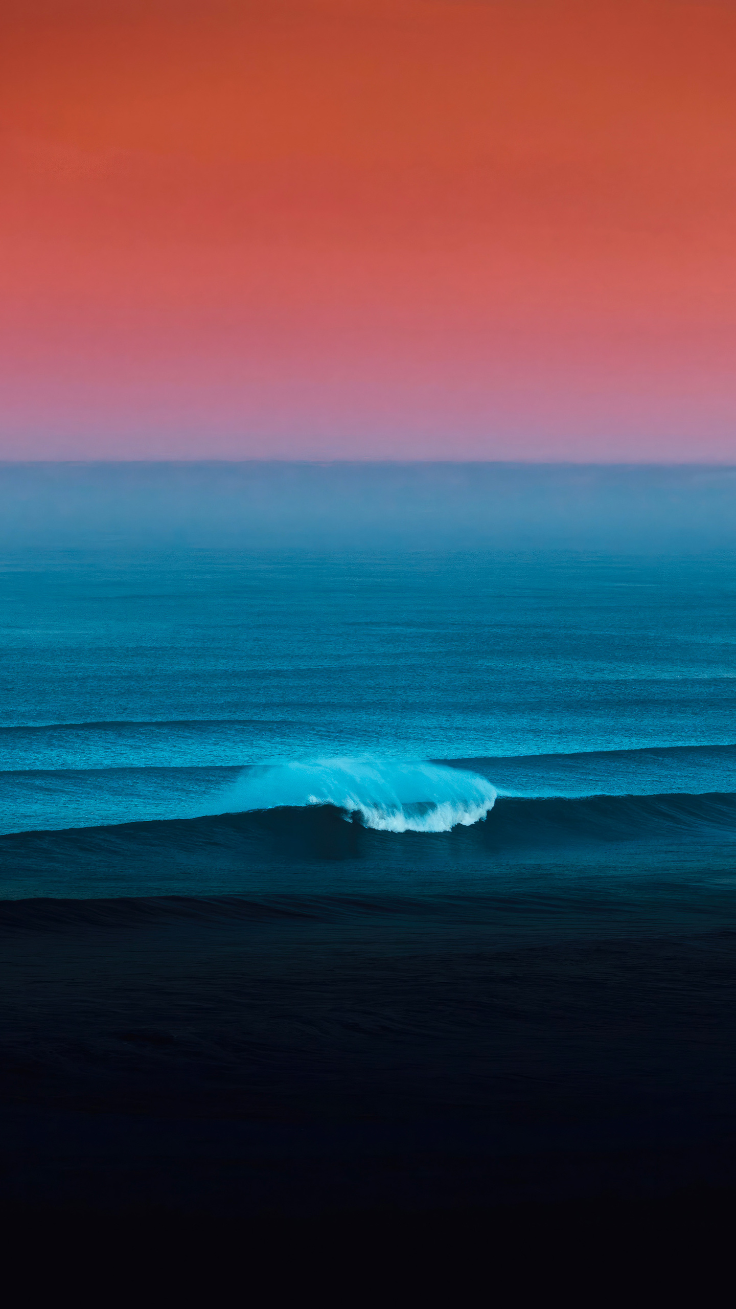 A lone surfer rides a wave under a vibrant, gradient sky.