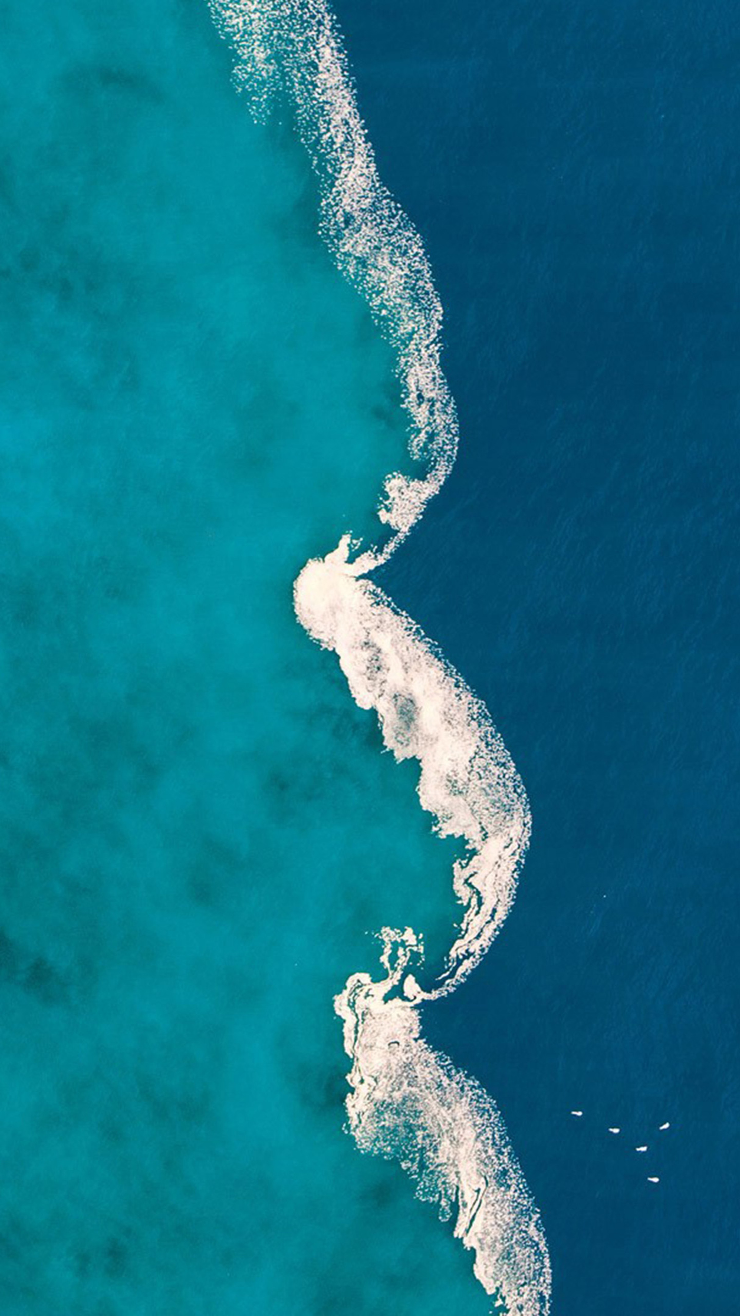 White sand islands emerge from a vast expanse of deep blue water.