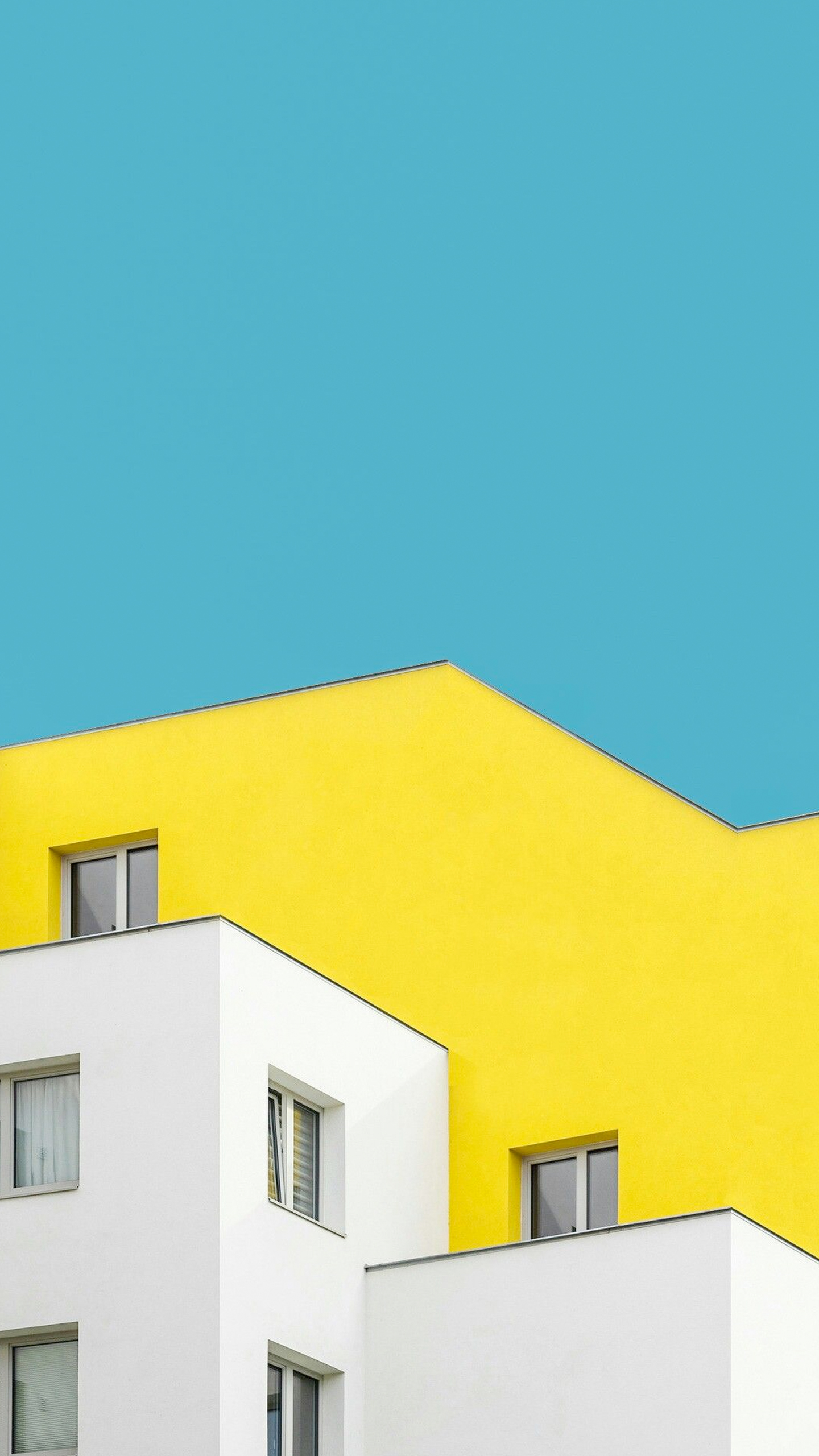 A striking white and yellow building stands against a vibrant blue sky.