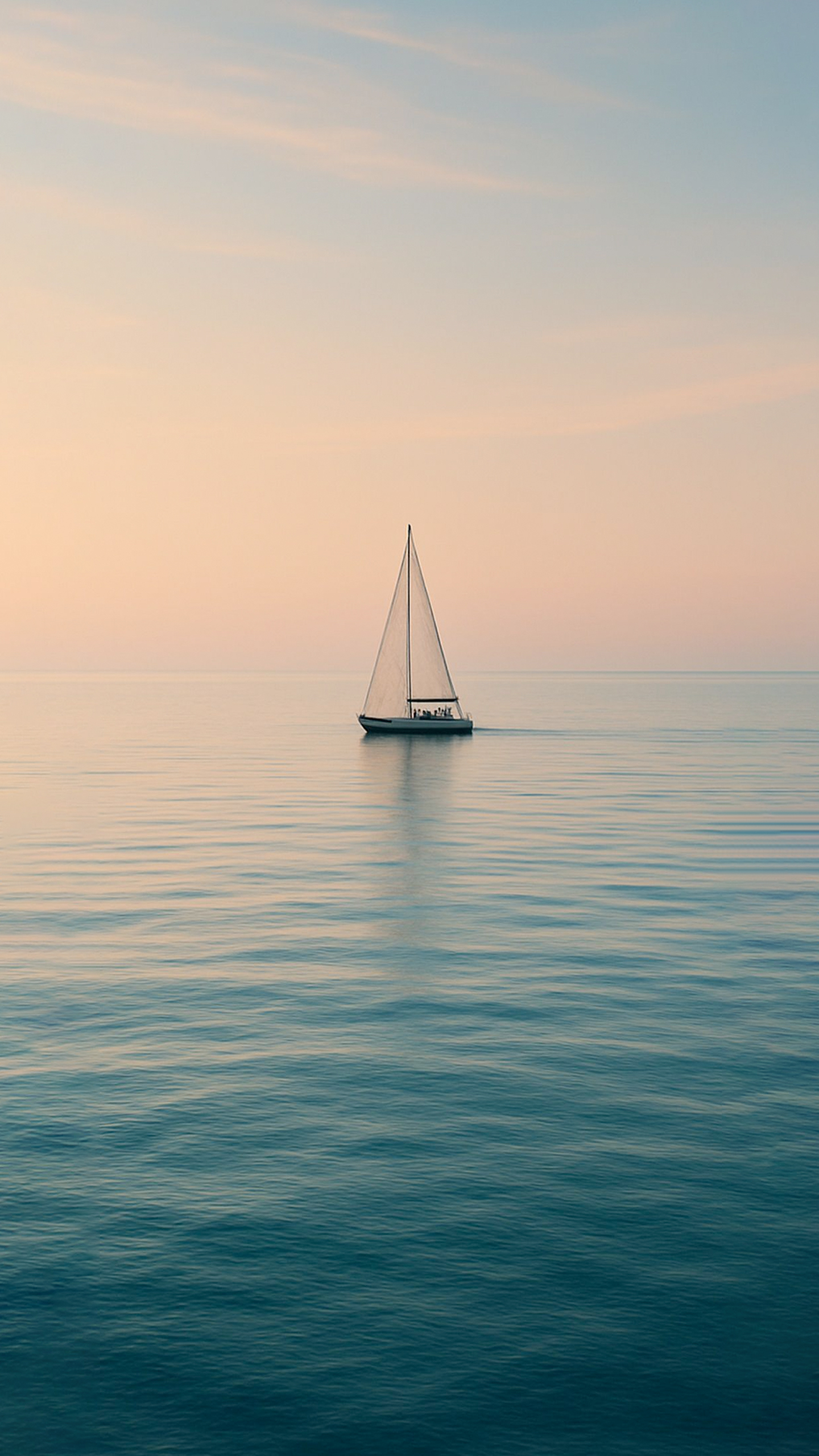 A serene sailboat glides across the calm, blue water, its white sails billowing gently in the breeze.