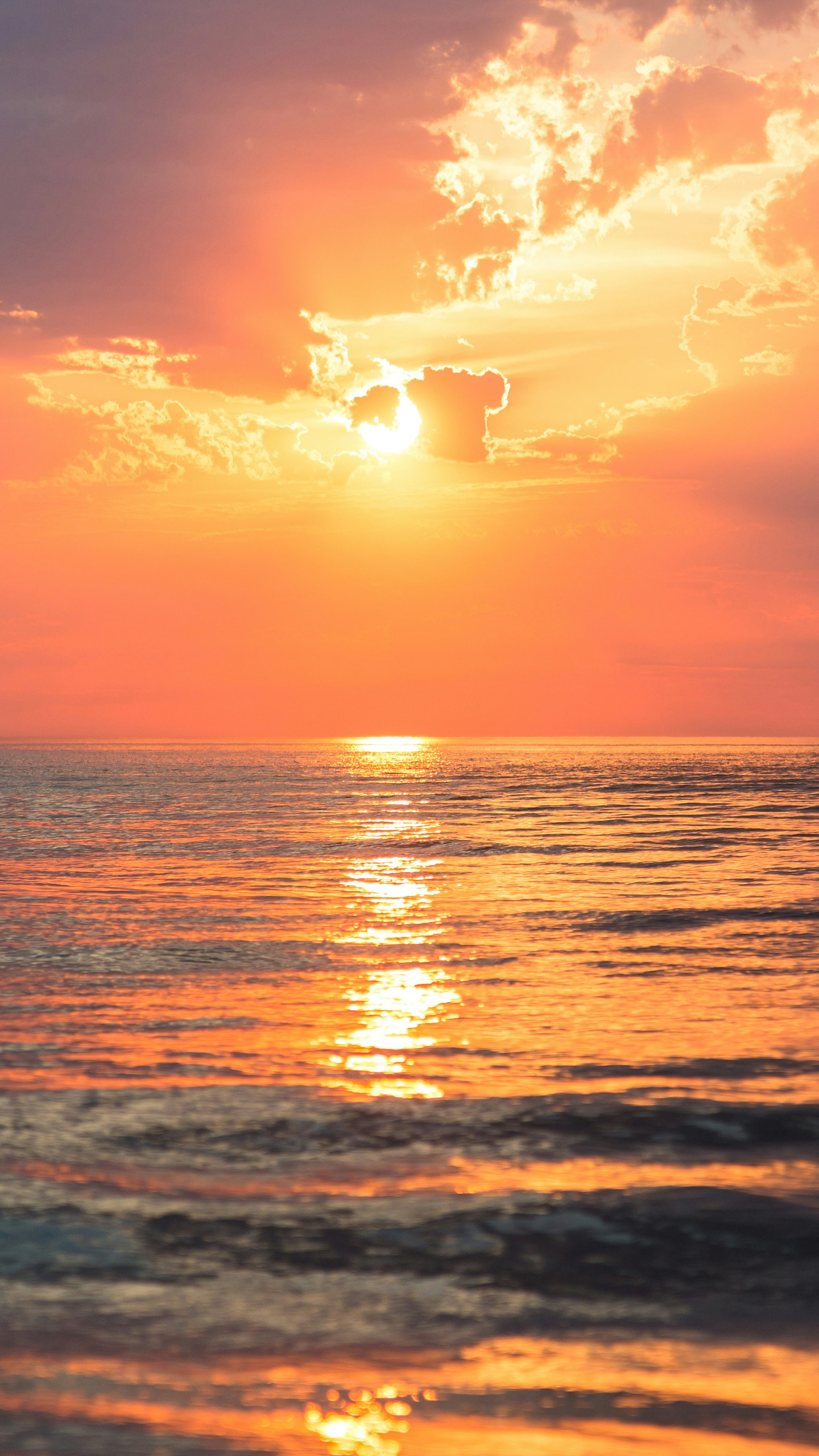 The sun sets over a vast body of water, casting a warm glow.