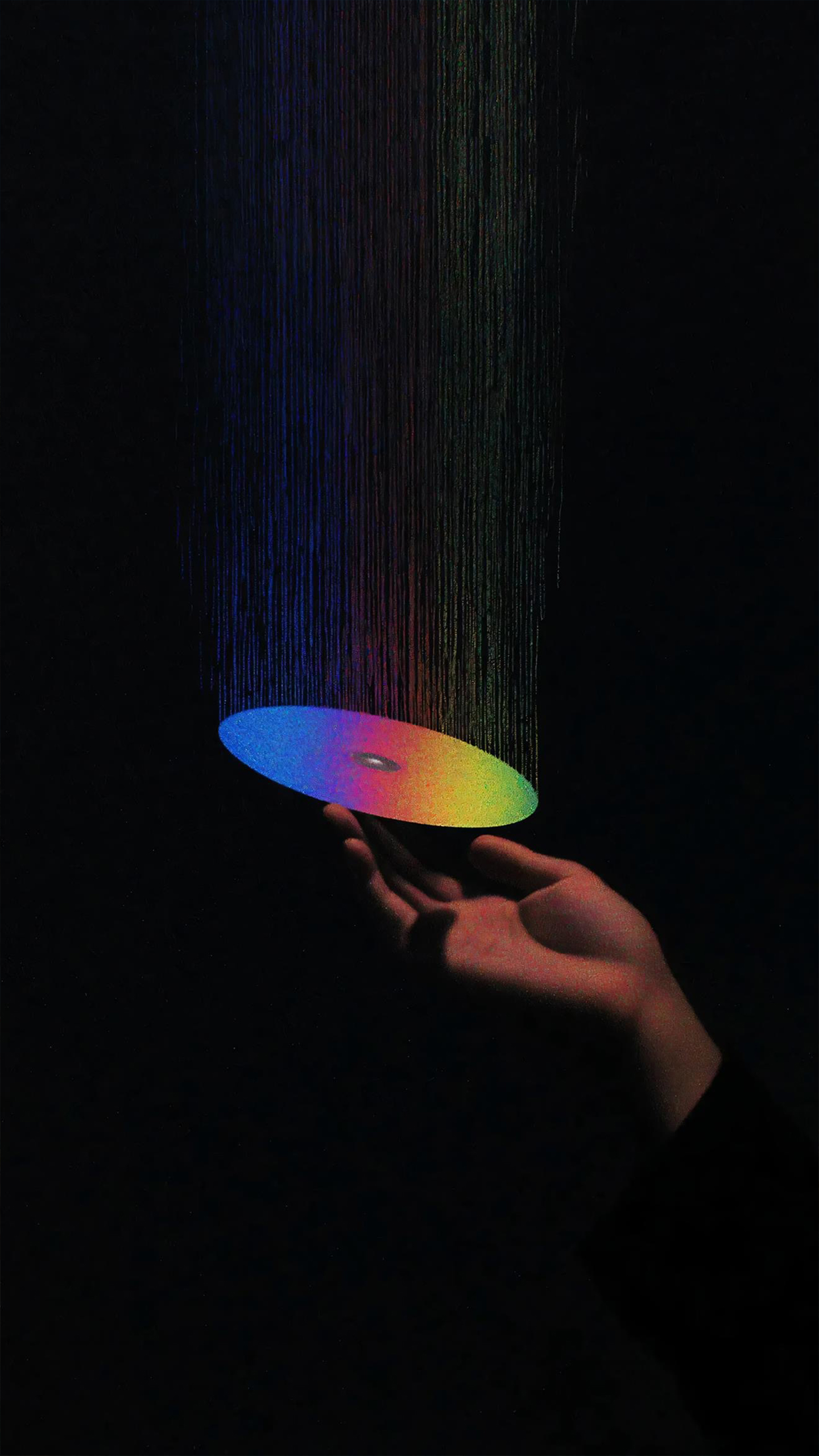 A rainbow-colored CD is being held by a hand, with a dark background.