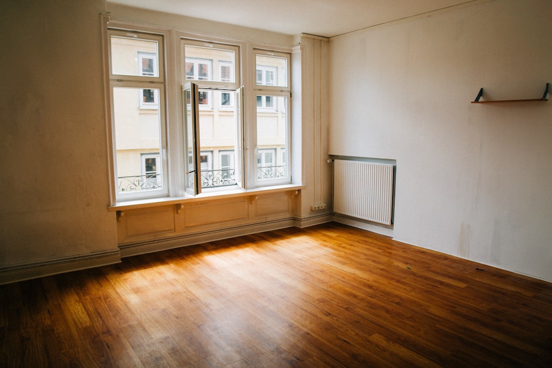 A room with wooden floors and large windows, bathed in natural light.