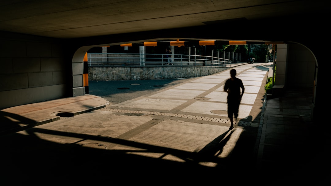 A person is running in a tunnel, their shadow stretching out in front of them.