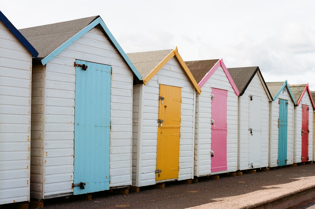 A row of small, colorful beach huts stands in a line.