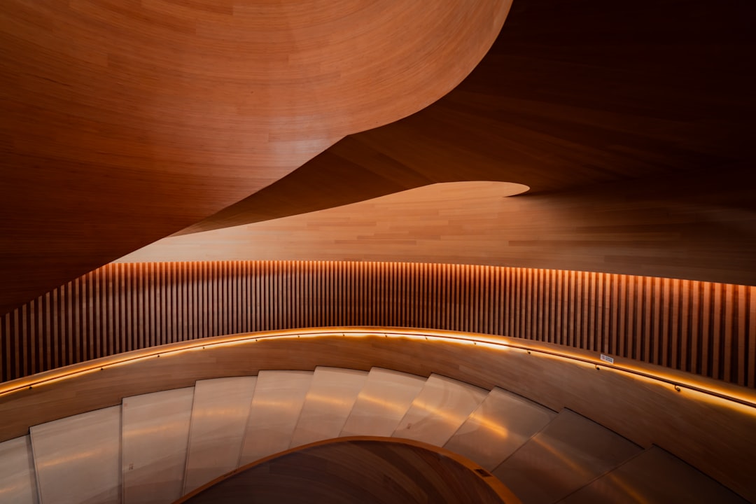 A spiral staircase with curved wooden walls and a railing, featuring a warm and inviting atmosphere.