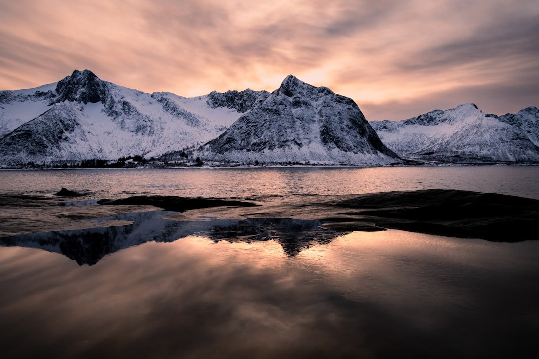 Snowy mountains are bathed in sunset light.