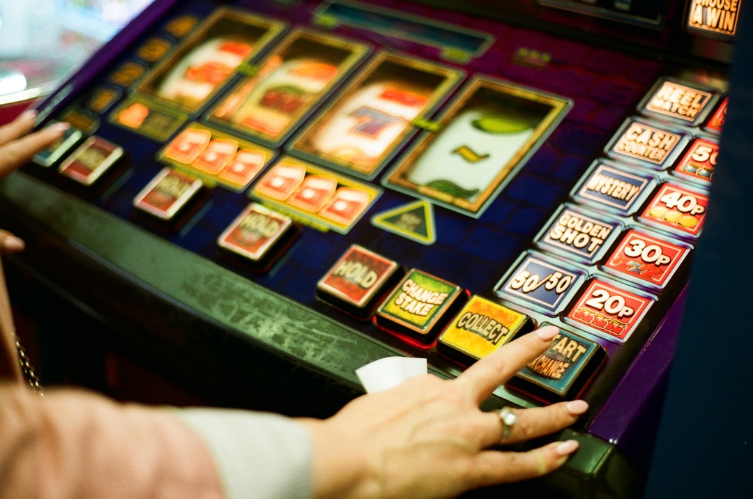 A person's hands are poised over a vibrant slot machine, with a blurred background suggesting a bustling casino atmosphere.
