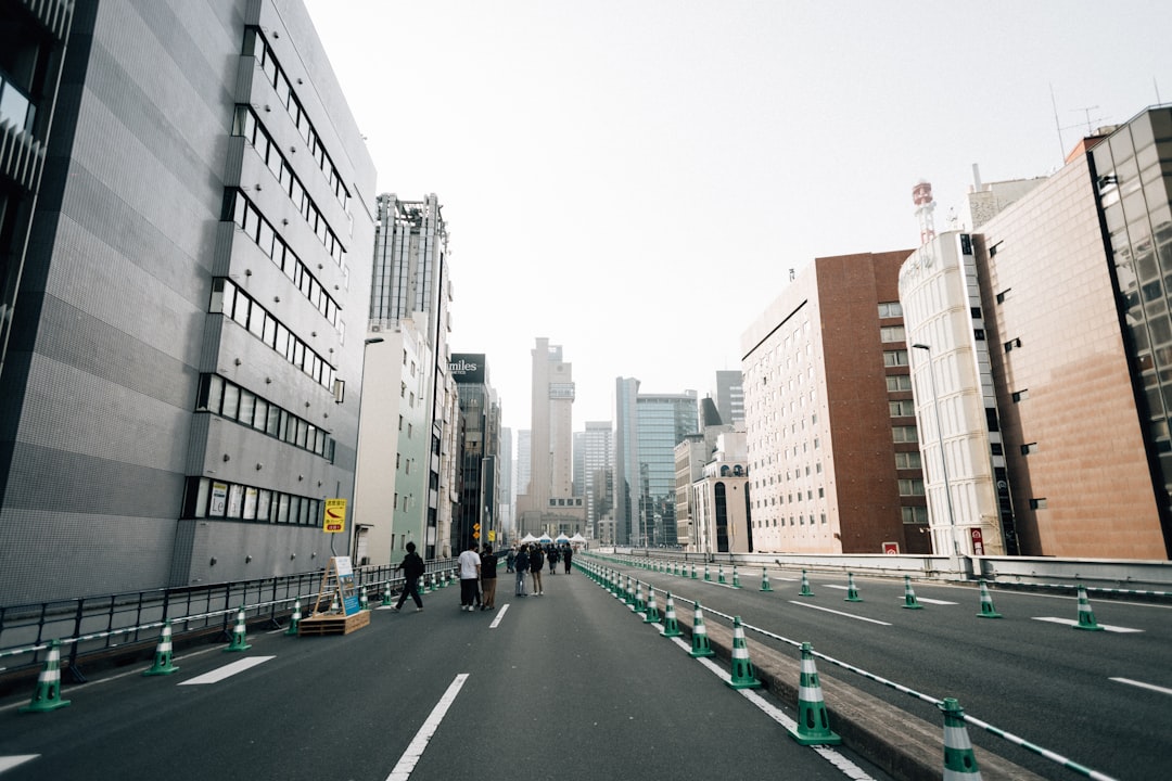 A city street with tall buildings on either side, and a group of people walking down the middle.