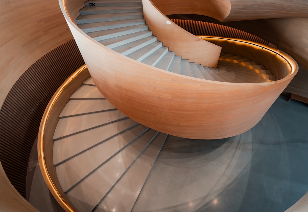 A light wood spiral staircase with a central railing and gray steps.