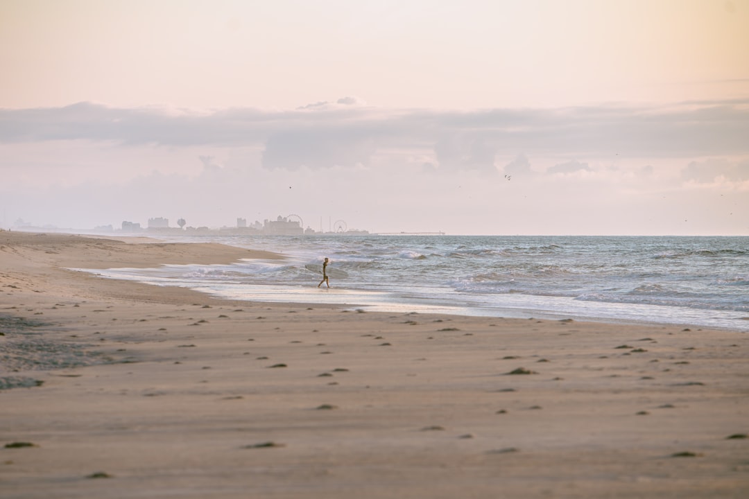 A lone figure walks along the beach, with the ocean stretching out before them.