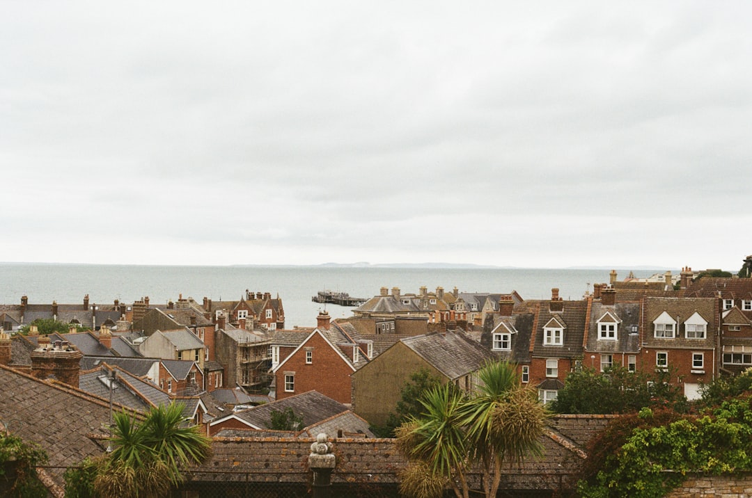 A coastal town with a mix of red brick buildings and palm trees under a cloudy sky.