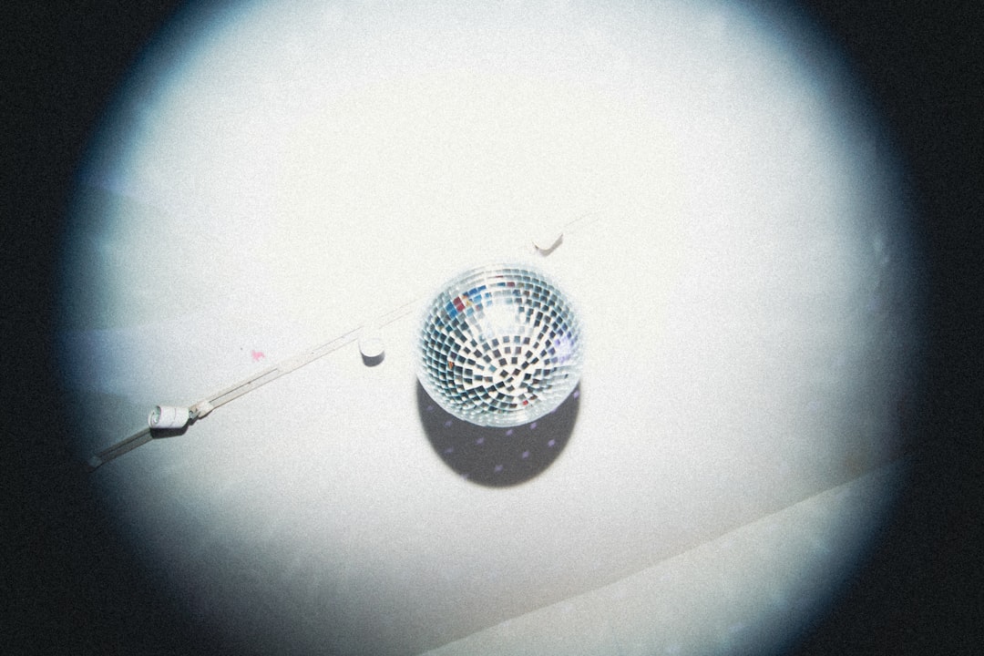 A disco ball hangs from the ceiling, casting a shadow on the white wall.