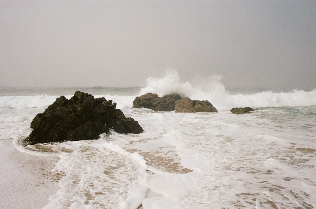 A rocky shoreline, with waves crashing against the shore, creates a serene yet dynamic scene.