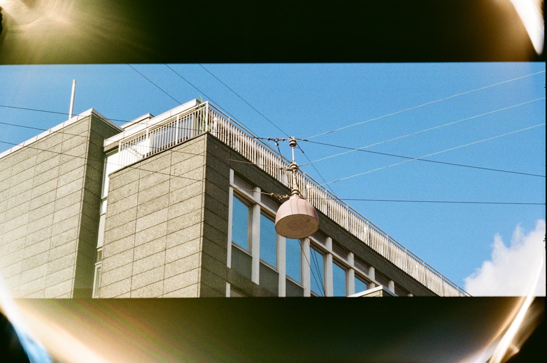 A large building with a balcony and windows stands against a blue sky.
