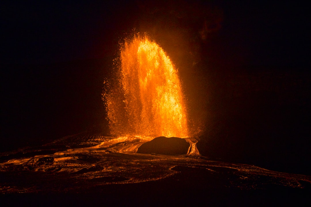A fiery volcanic eruption illuminates the dark landscape.