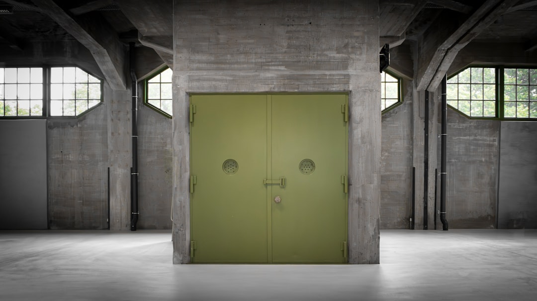 A large green metal door stands prominently in the center of a spacious room.