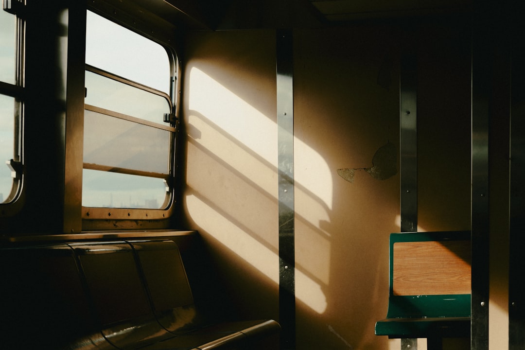 A train car with a window and empty seats, bathed in sunlight.