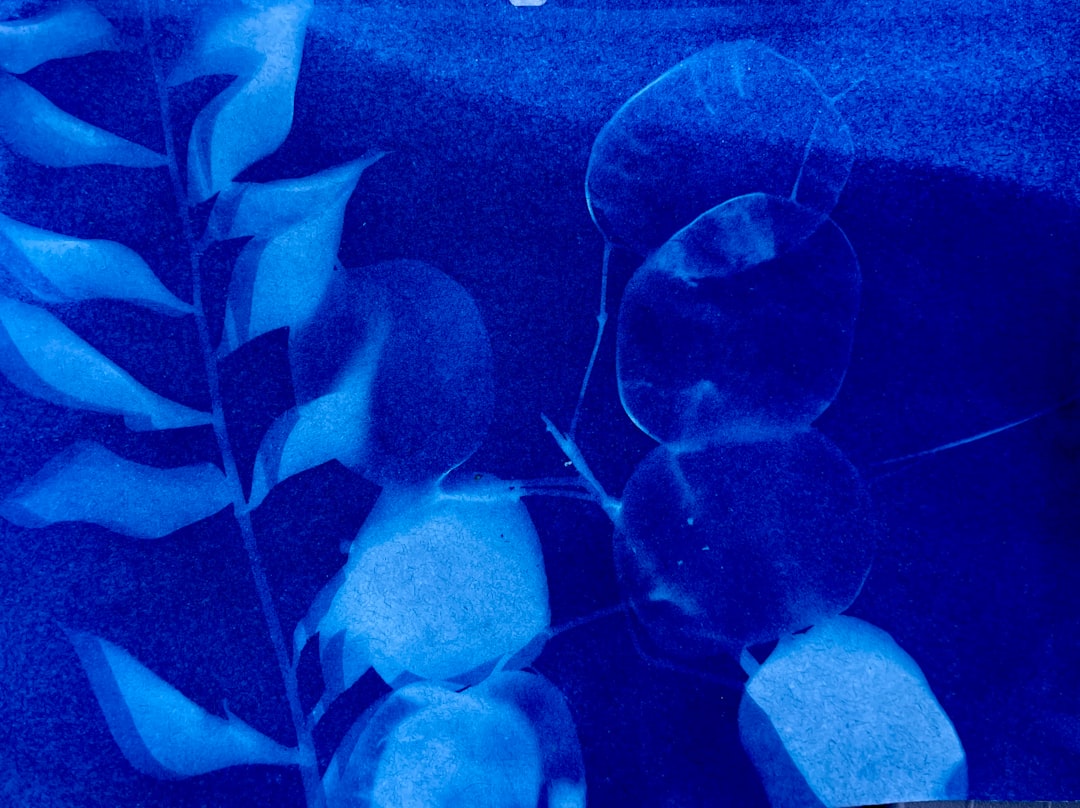 A vibrant blue-toned photograph of a plant with leaves and stems, showcasing its intricate details.