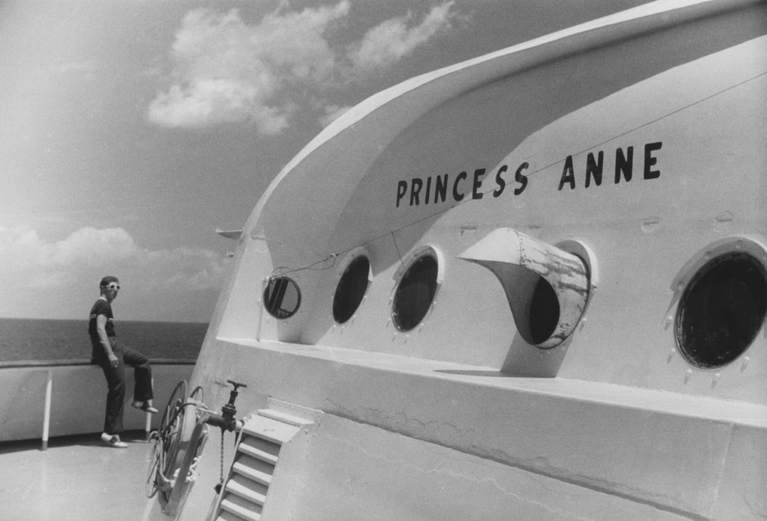 A man stands on the deck of a ship, gazing out at the vast ocean.