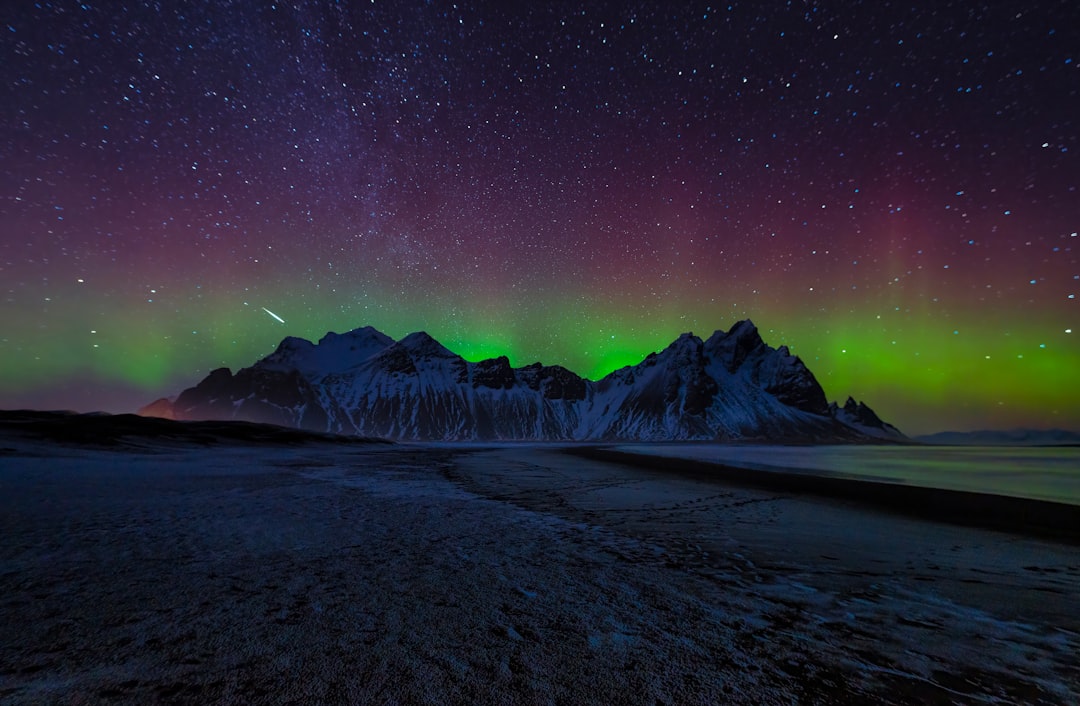 A breathtaking night sky with the Northern Lights dancing above snow-capped mountains.