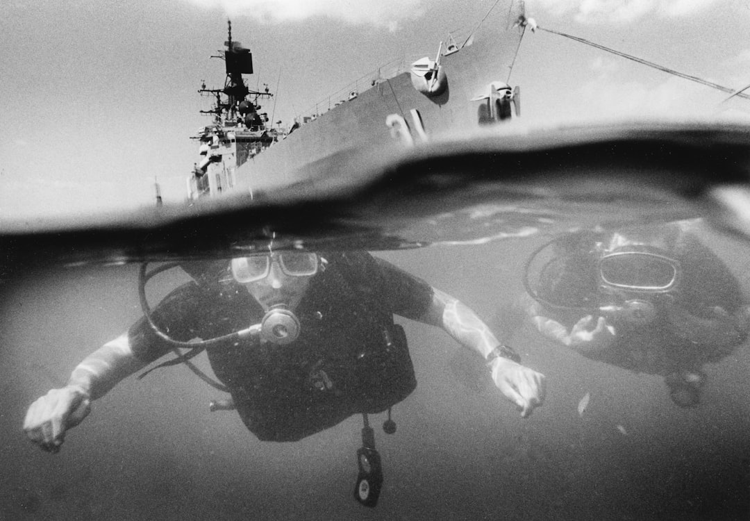 A scuba diver swims beneath the hull of a warship.