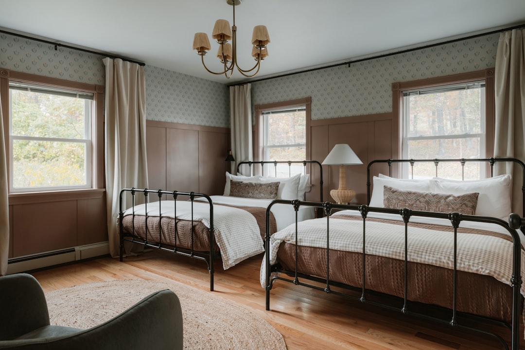A serene room with two beds, a chandelier, and a window, exuding warmth and comfort.
