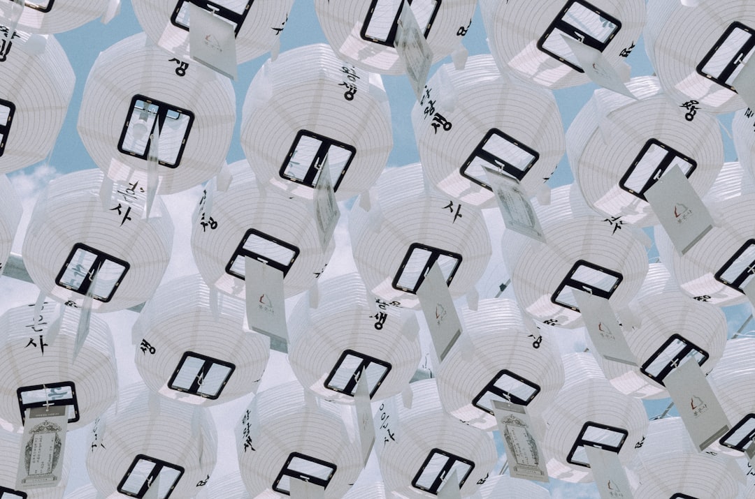 A multitude of white paper lanterns suspended against a blue sky.
