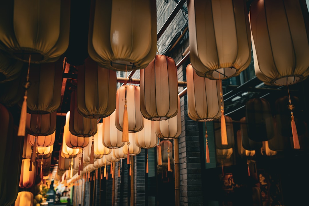 Rows of lanterns hang against a brick wall.
