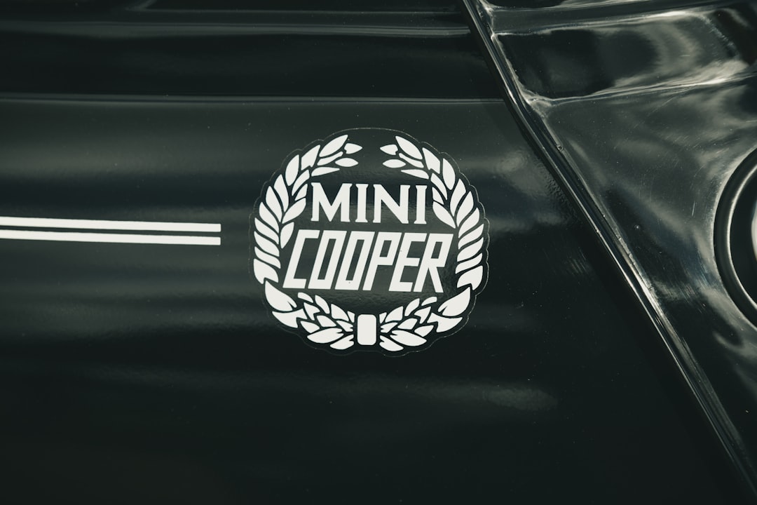 A logo featuring the words "MINI COOPER" surrounded by a wreath, situated on the side of a black car.