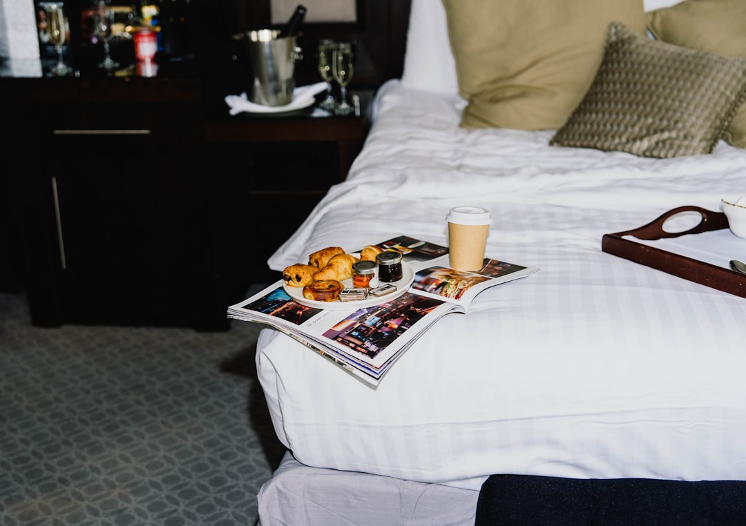 A bed with a tray of pastries and a coffee cup on it.