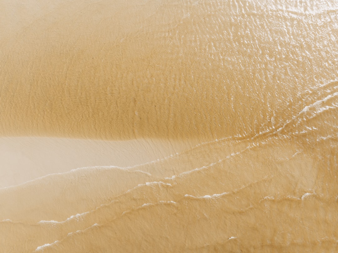 Shimmering beige leather with subtle creases and a glossy finish.
