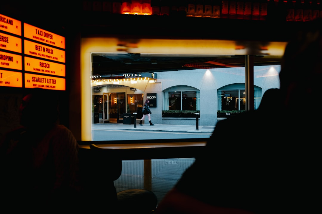A woman in a black jacket walks past a white building.