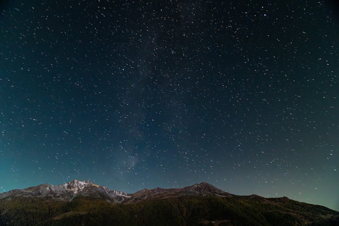 Snow-capped mountains stretch under a star-filled sky.