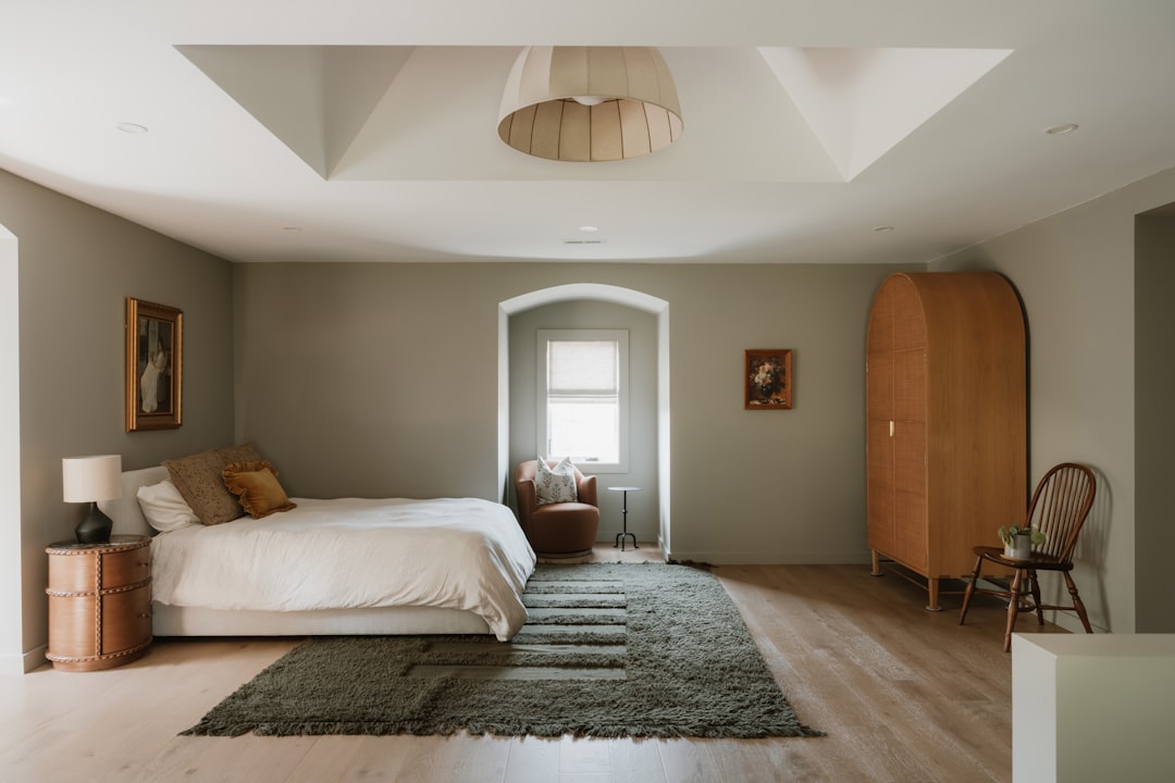 A cozy bedroom with a plush bed and a dark green rug.