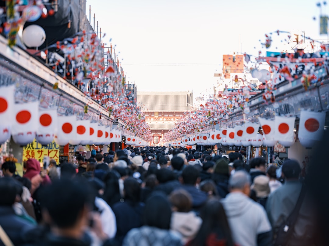 A bustling street in Tokyo, Japan, lined with red and white lanterns, teeming with people.