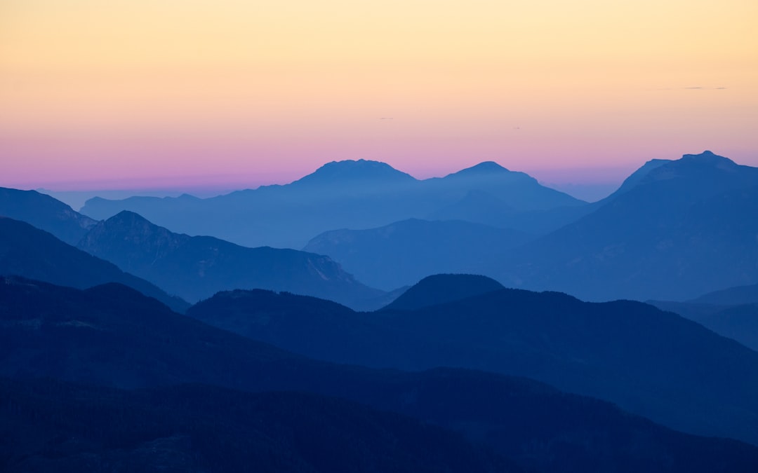 Silhouetted mountains stand tall against a vibrant, gradient sky.