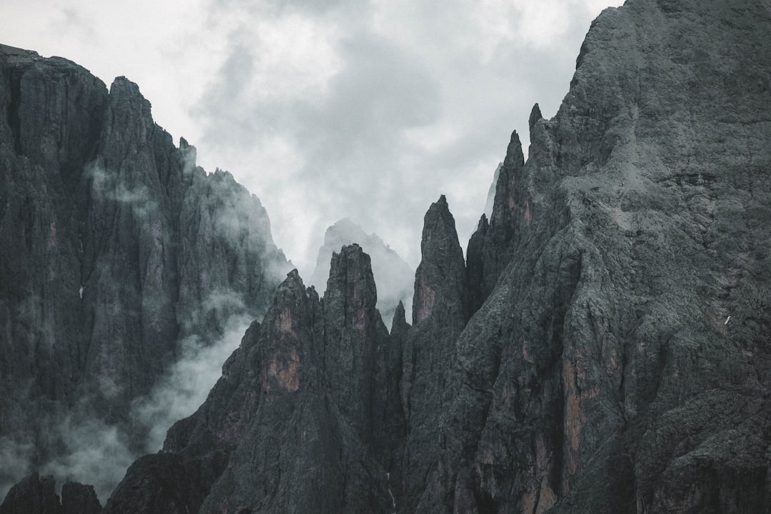 Towering mountains stand against a cloudy sky.