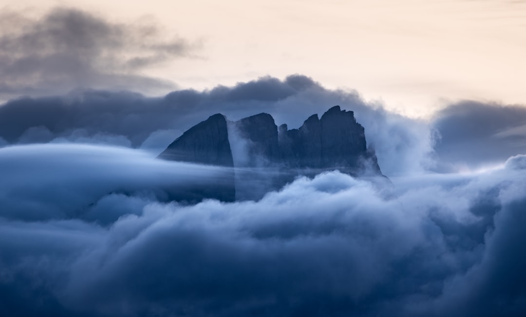 A majestic mountain range stands tall amidst a sea of clouds, its rugged peaks piercing the sky.