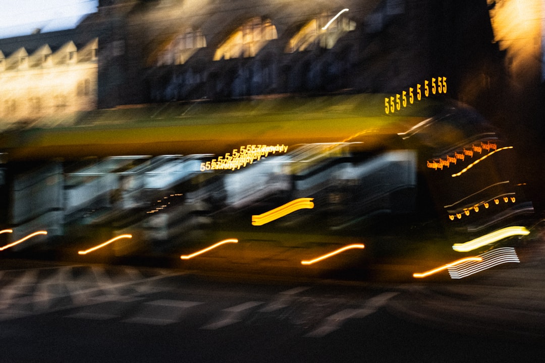 A blurry nighttime scene unfolds with a large building and a row of lights, evoking a sense of movement and energy.