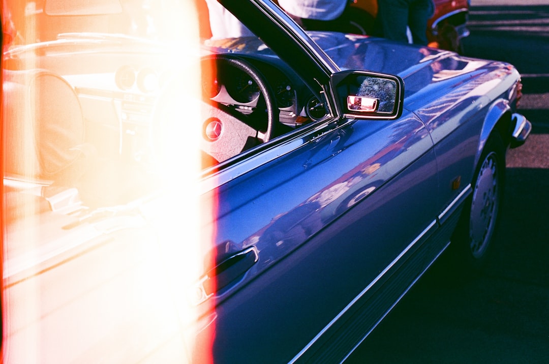 A blue car with its top down and side mirror visible.