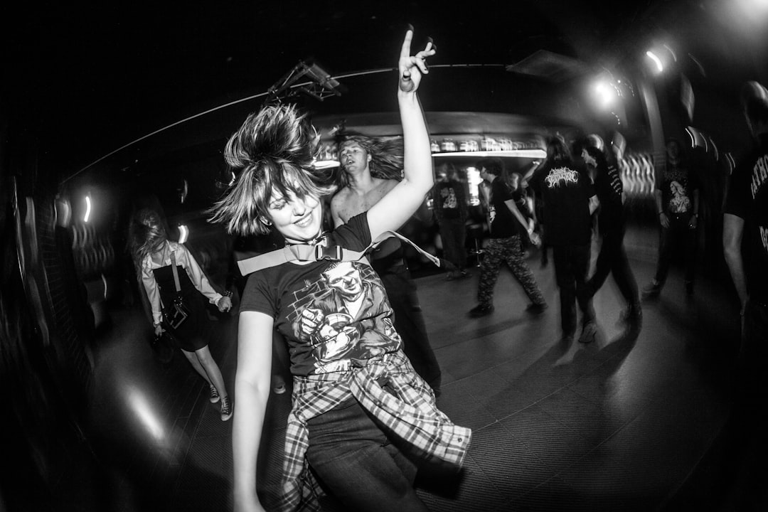 A person with their arms raised, dancing with a crowd in the background.