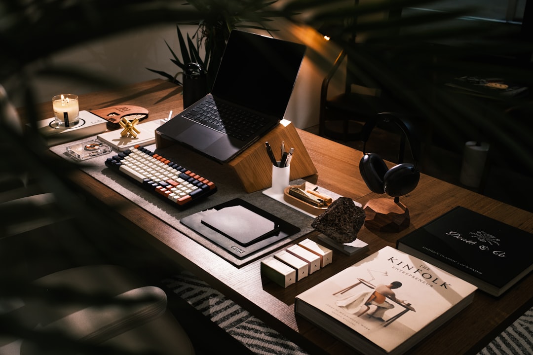 A wooden desk is set up with a laptop, books, and office supplies.