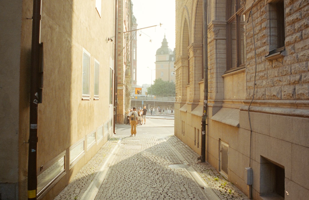 A narrow cobblestone alleyway is bathed in warm sunlight.