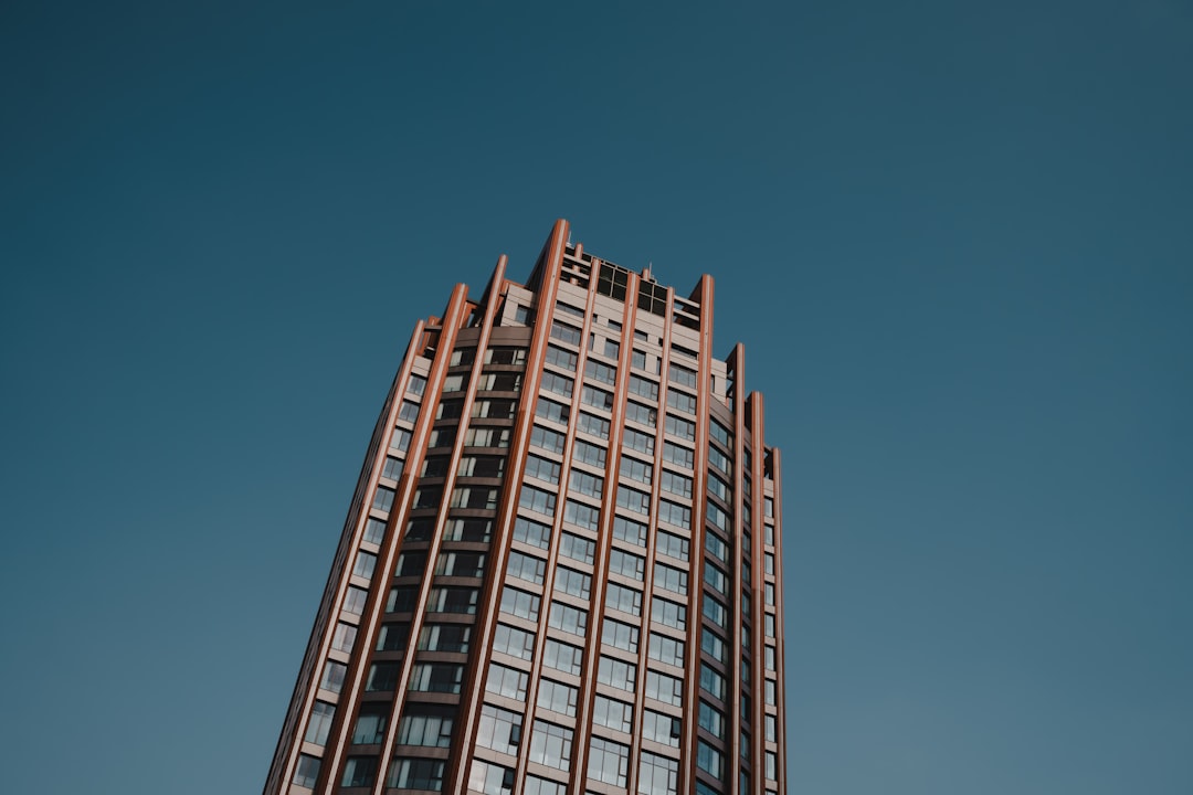 A towering skyscraper rises against a clear blue sky.