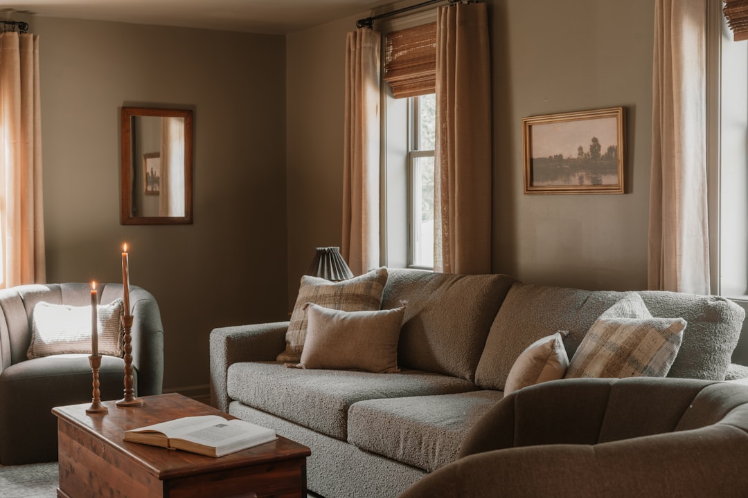 A cozy living room with a gray couch, wooden coffee table, and warm candlelight.