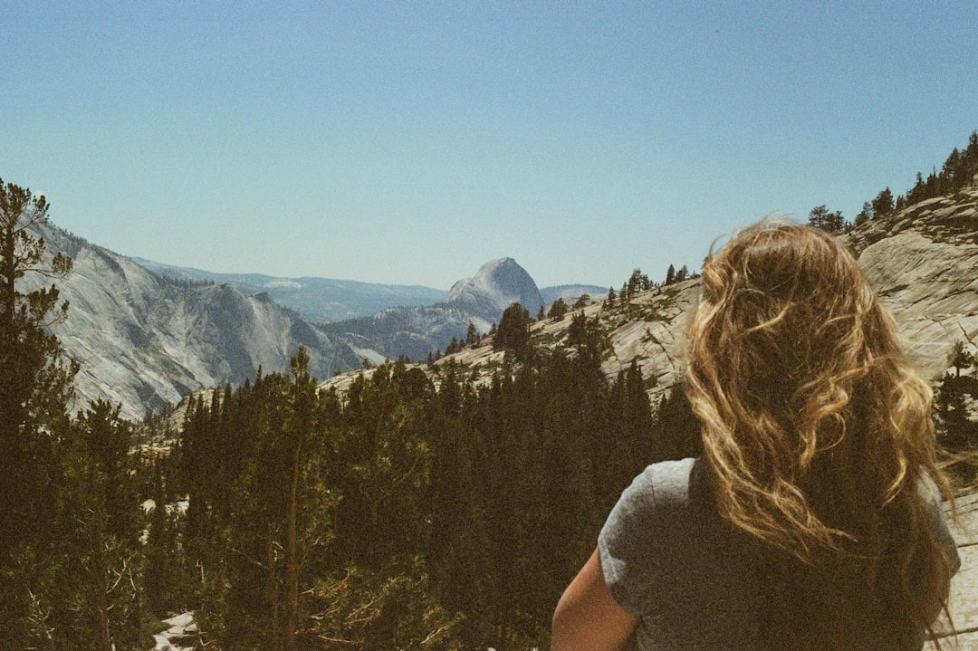 A woman with long hair gazes out at a mountainous landscape.