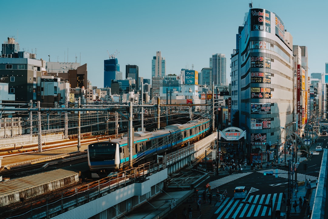 A bustling cityscape unfolds, with a train hurtling through a station amidst towering skyscrapers and neon-lit billboards.